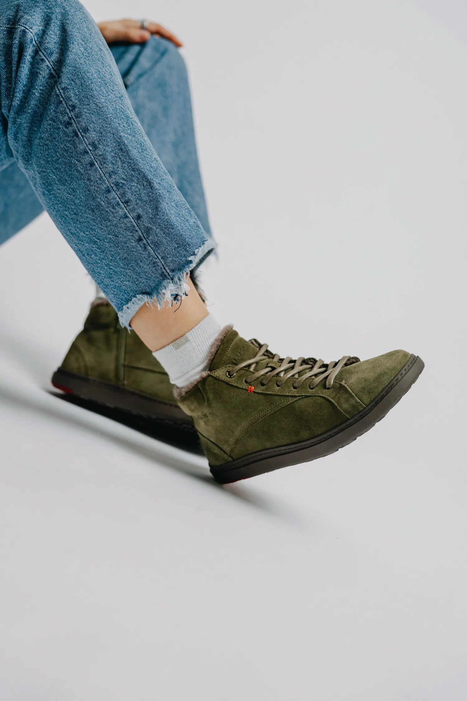 Person trägt olivegrüne, gefütterte High-Top Wildleder-Sneaker Modell BLSN-030W von Blusun zu einer blauen Jeans.
